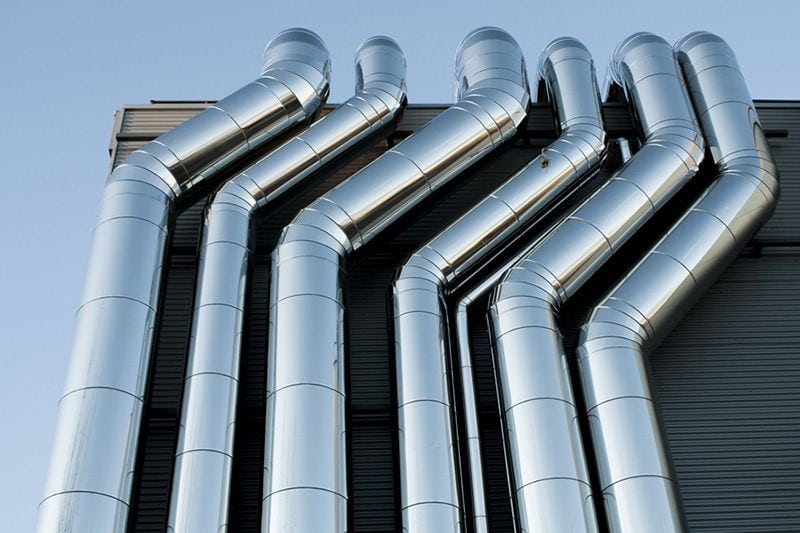 6 commercial pipes side by side on a building. Zone Control Systems for Commercial Buildings.